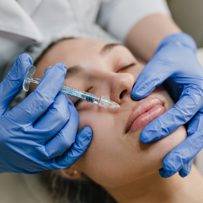 Closeup portrait young woman doing botox procedures by professional. Injection, making lips, modern devices, technology, medicine, cosmetology therapy