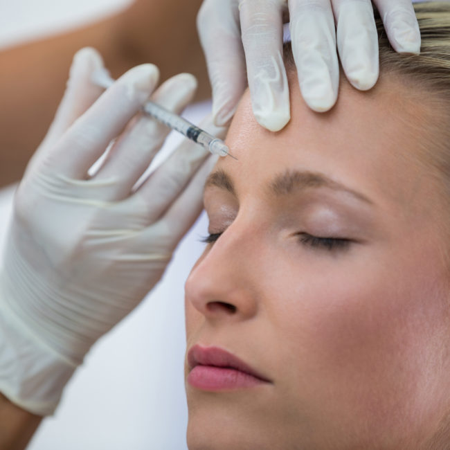 Close-up of female patient receiving a botox injection on forehead